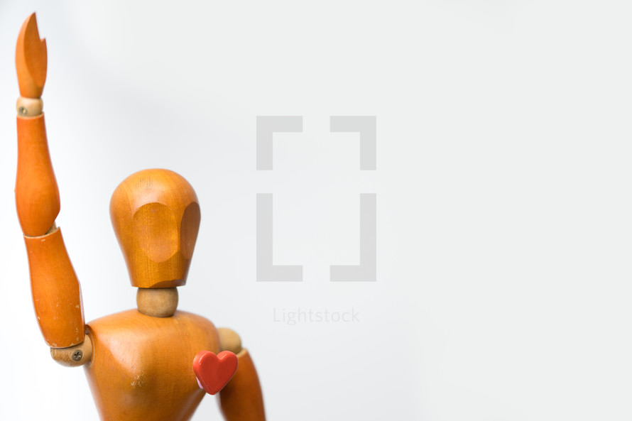Wooden model character of woman standing and raise hand alone with one heart shape in her heart white background