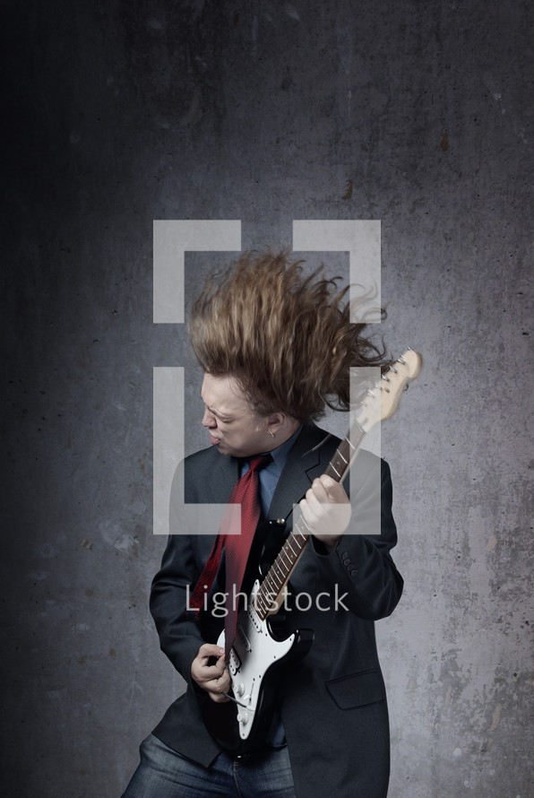 a man in a suit and tie jamming on a guitar 