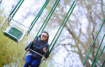 a woman on swinging chairs at an amusement park 