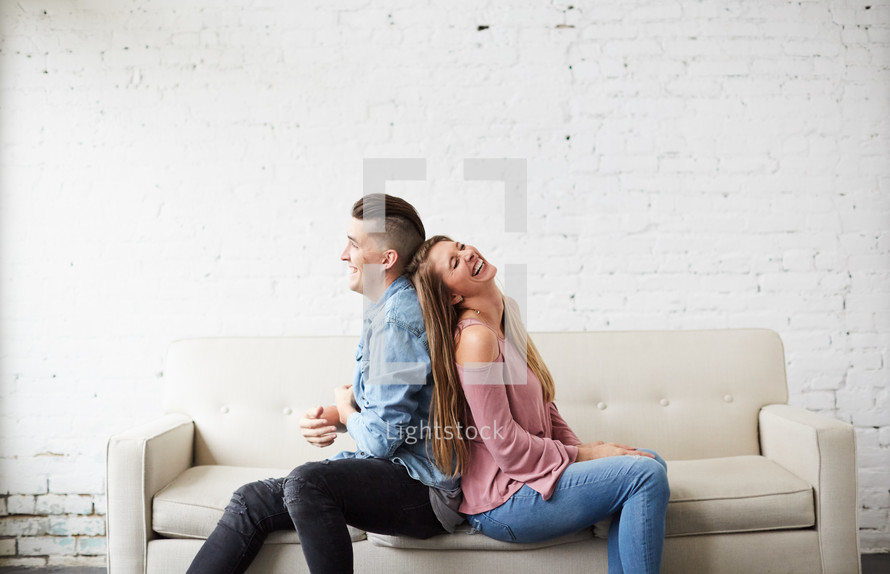 a couple sitting on a couch talking and laughing 