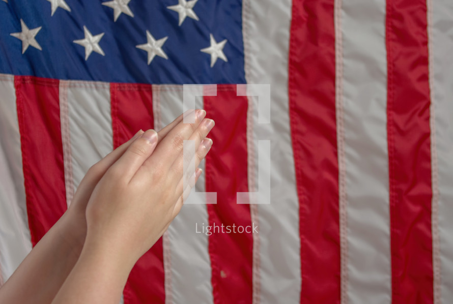 praying hands and an American flag 