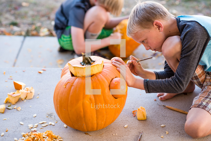 a boy child carving a pumpkin 
