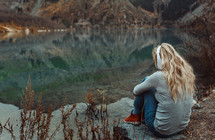 a woman listening to headphones by a lake 