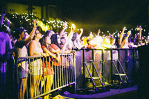 cheering fans at a concert holding lighters and glowing cellphones 