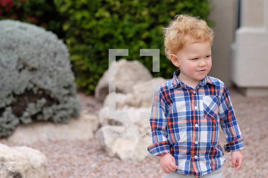 toddler boy in a plaid shirt outdoors 