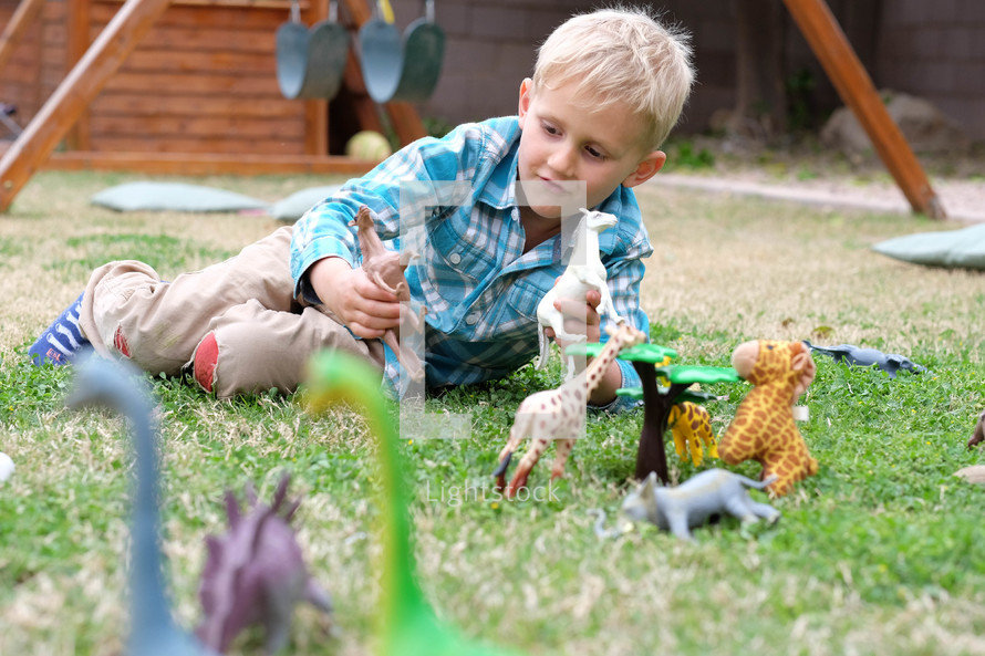 boy playing with toy animals in the grass
