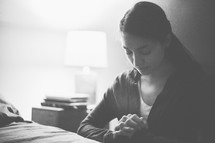 A woman praying beside her bed 