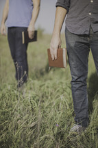 men holding Bibles at their sides standing in a field of tall grass 