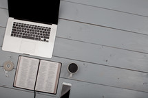 a laptop computer, earbuds, coffee mug, cellphone, and Bible sitting in a coffee house 