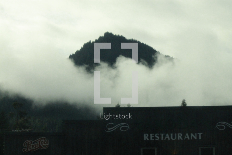 clouds and a mountain top and a restaurant sign 