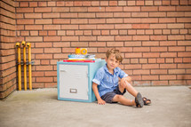 a boy sitting by a locker next to books 
