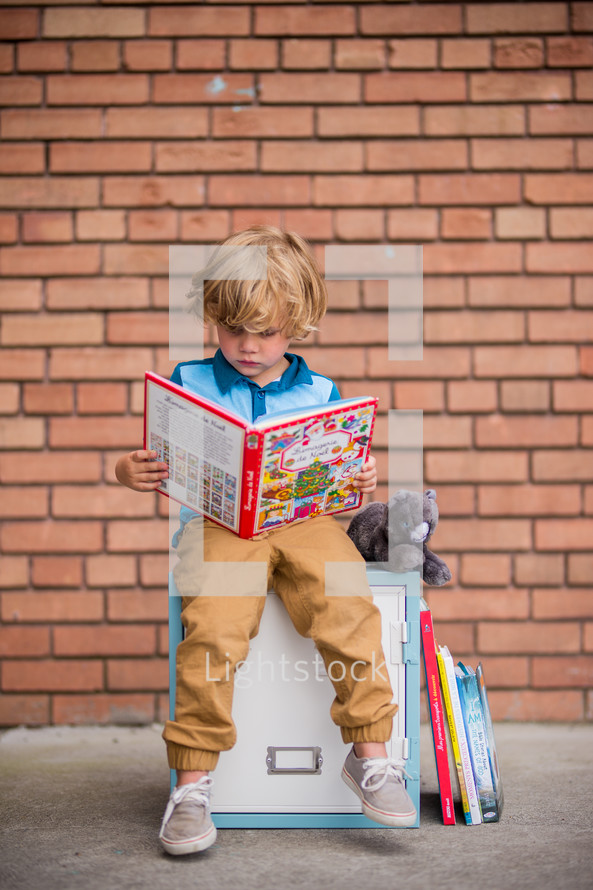 a child sitting on a locker reading a book 