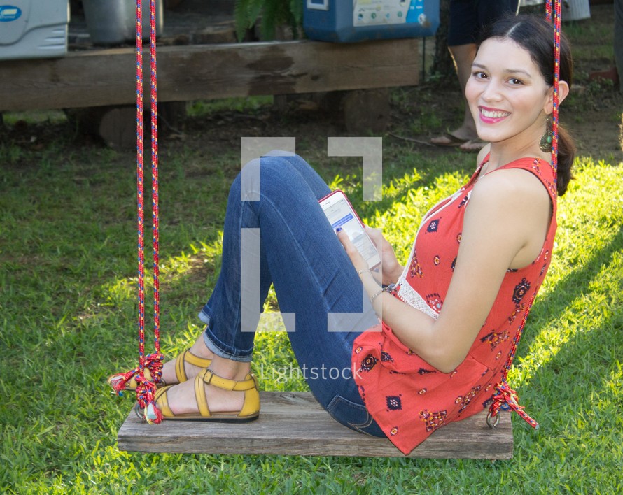 a woman sitting on a swing reading 