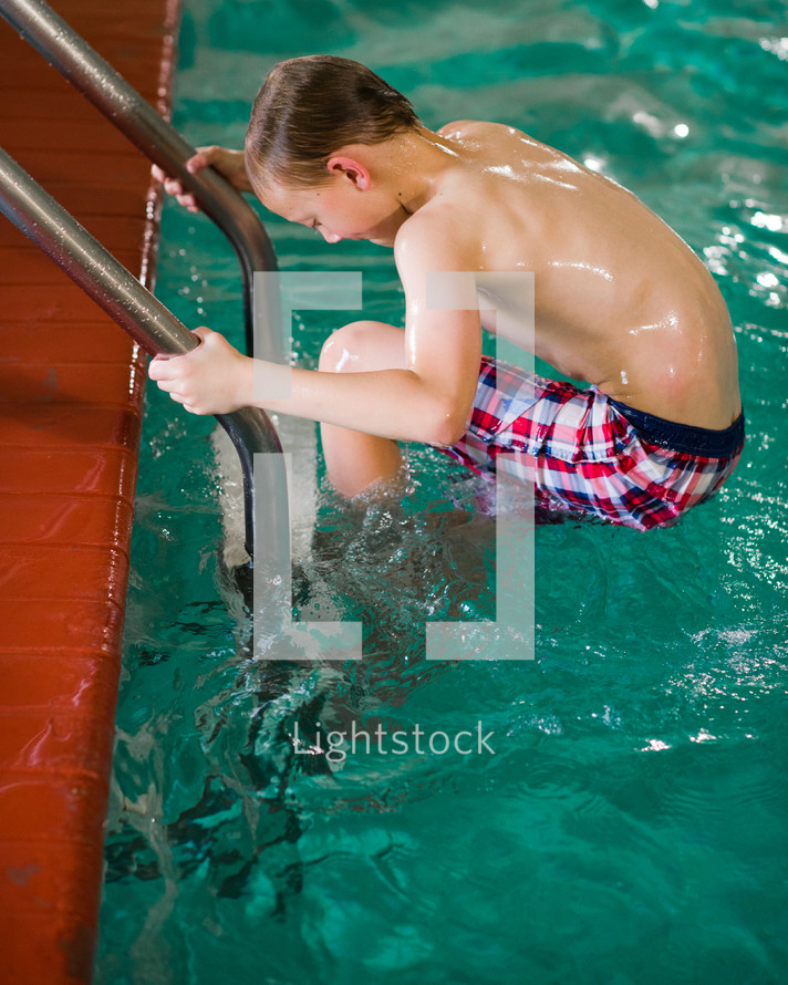 a boy climbing out of an indoor pool 