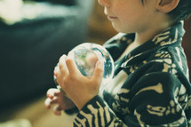 a boy child holding a snow globe 