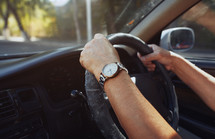 man's hands on a steering wheel 