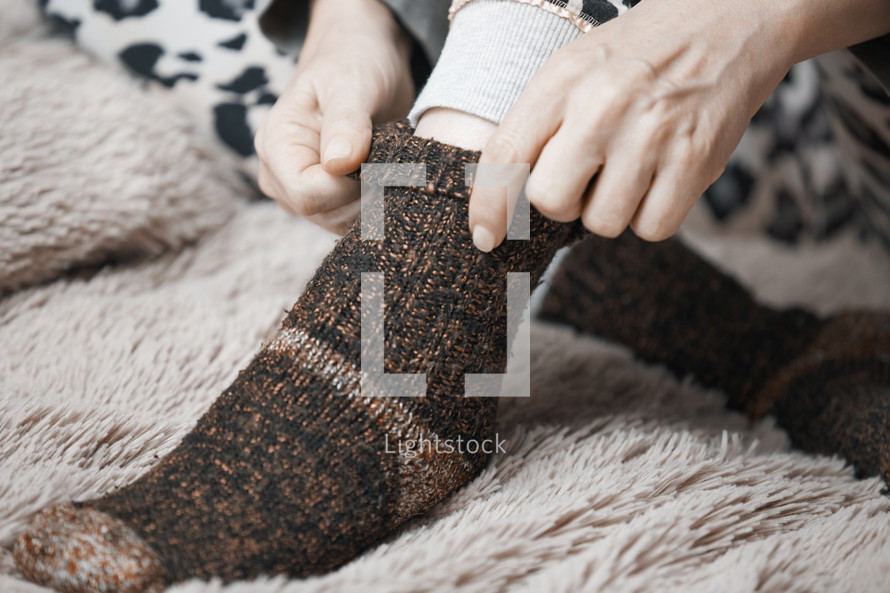 a woman putting on warm cozy socks 