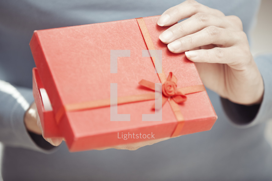 a woman opening a red gift box 