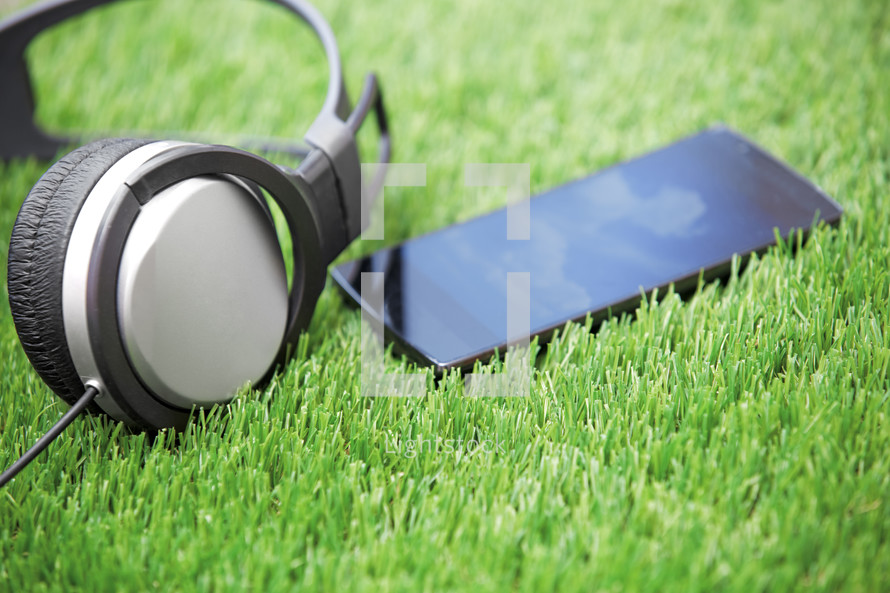 Headphones and smartphone lying on a grass