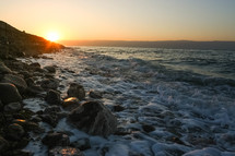 Waves crashing onto the shore of the Dead Sea at sunset