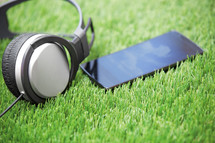 Headphones and smartphone lying on a grass