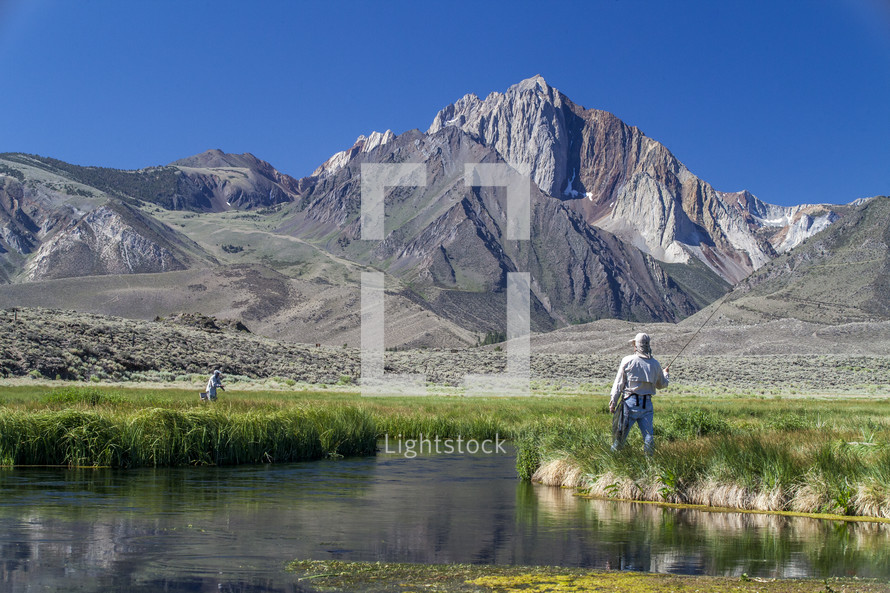 fly fishing in a river near a mountain 
