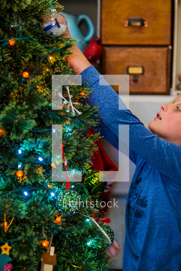 a boy decorating a Christmas tree 