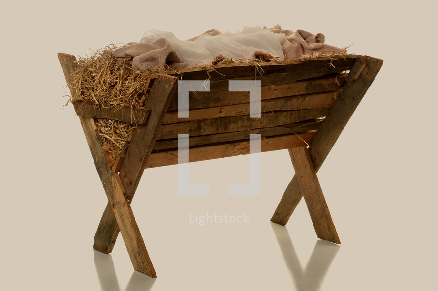 Swaddling clothes in a wooden manger filled with hay.