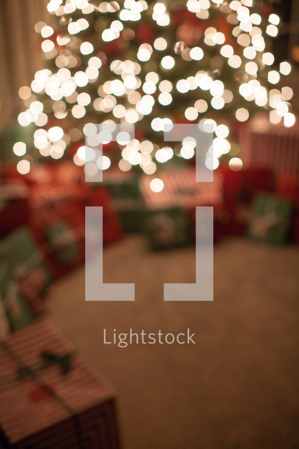 gifts under a Christmas tree and bokeh white Christmas lights 