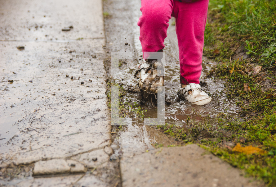 a toddler girl walking through mud