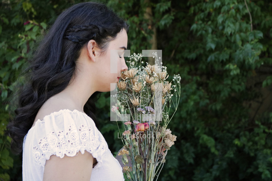 girl in a white dress smelling flowers 