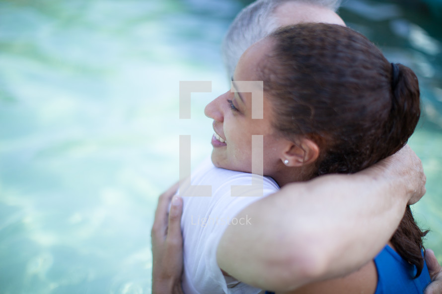 Man and woman hugging in a pool of water.