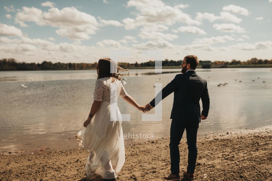 bride and groom walking holding hands on a beach 