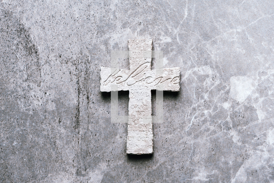 Stone cross with inscription Believe. 