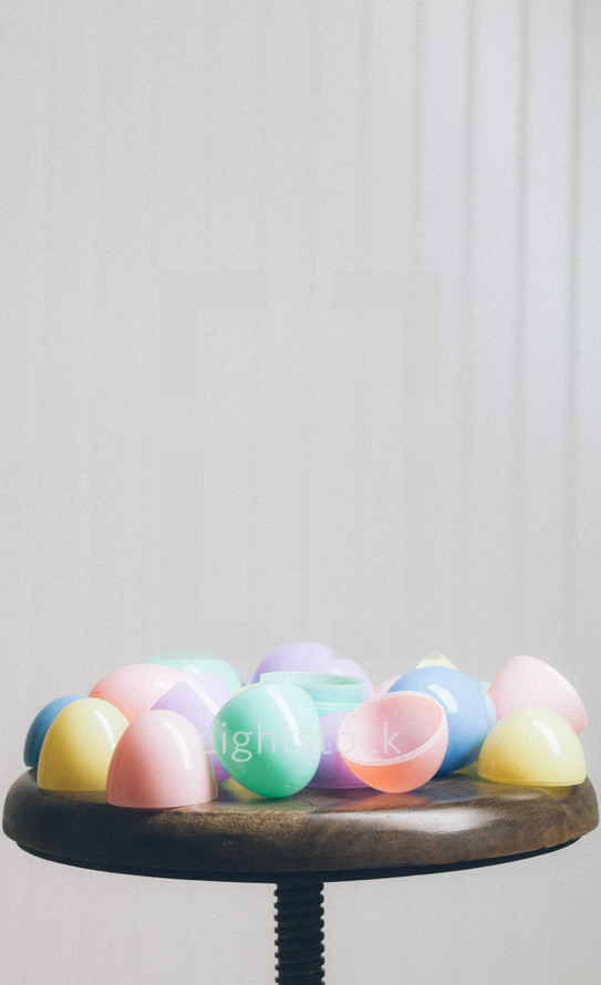 Colorful plastic Easter eggs on a wooden stool.