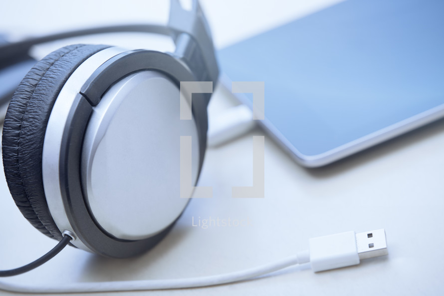 Headphones digital tablet and USB cable lying on a table
