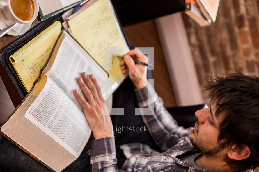 man reading a book and taking notes 