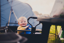 an infant in a wagon in front of a tent 