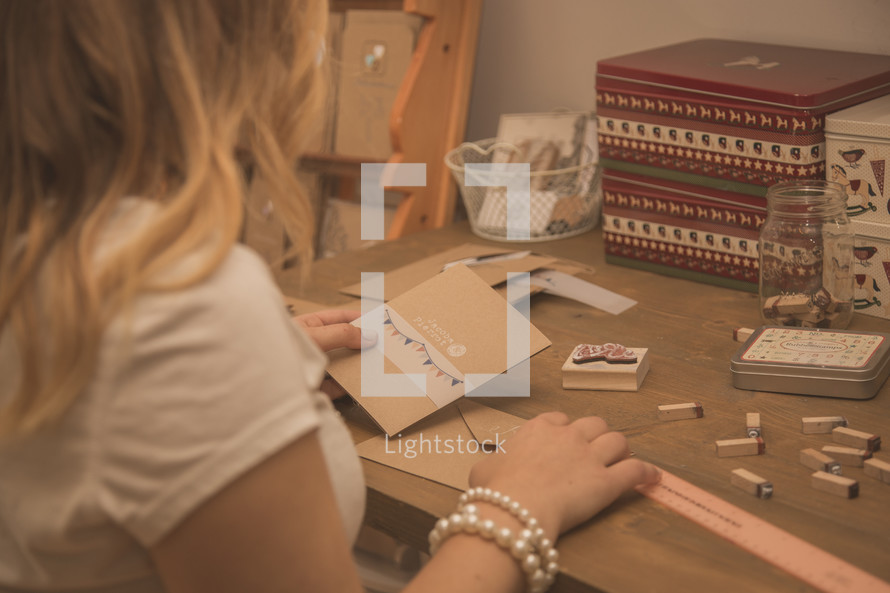 A woman sitting at a crafting desk working with stamps.