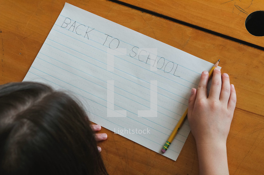 a girl writing Back to School on paper
