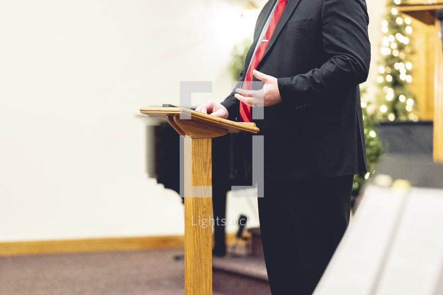 Man in a suit preaching at a podium