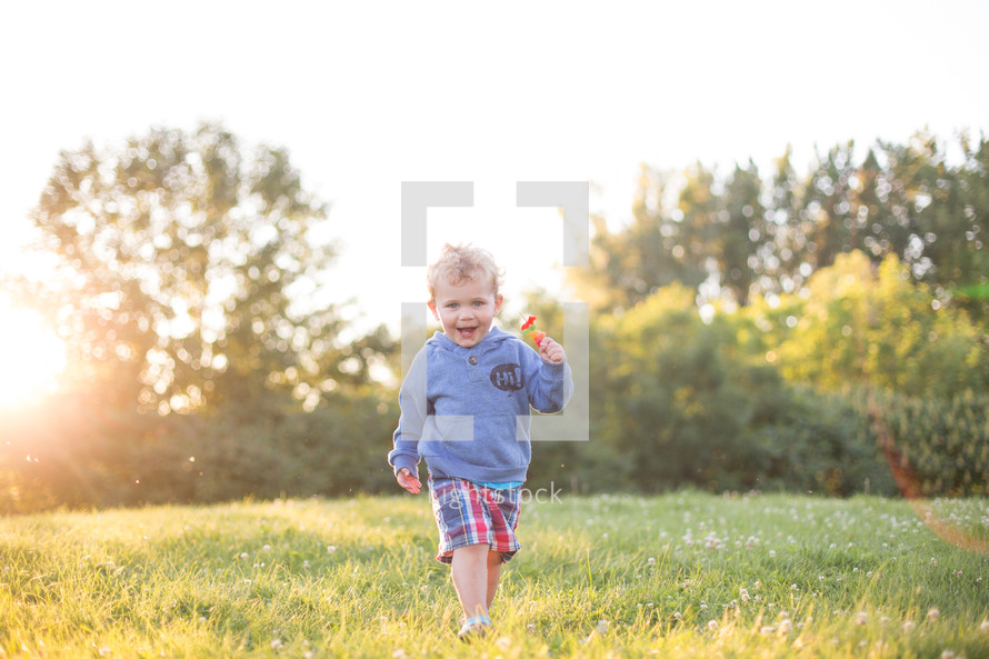 A little boy running in a field of grass.