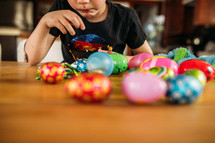child eating candy out of Easter eggs 