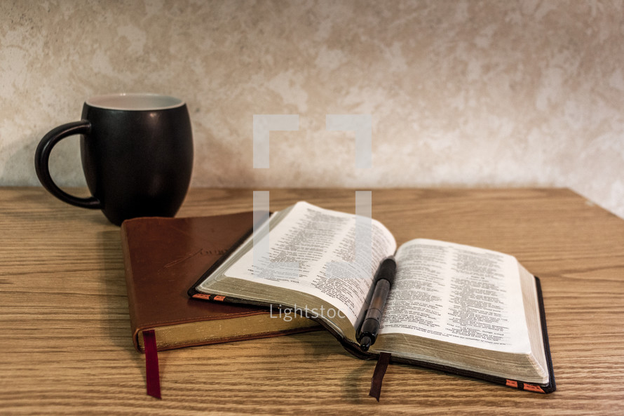 Bible open on desk with journal and black coffee cup