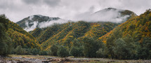 Foggy mountain forest and river valley in autumn 