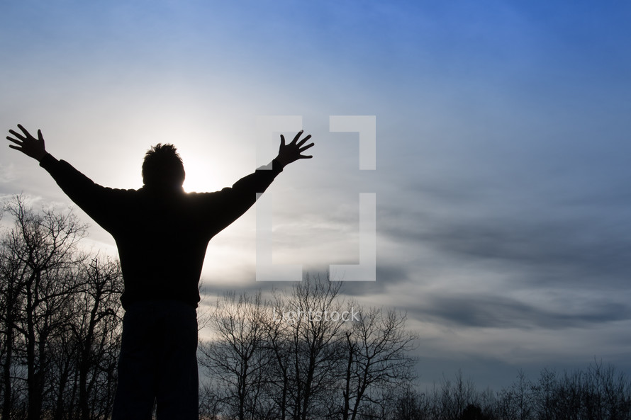 Man praising God in sunset with outstretched arms up