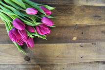 A bundle of purple tulips laying on a wooden surface.