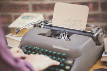 Hands typing on an old manual typewriter.