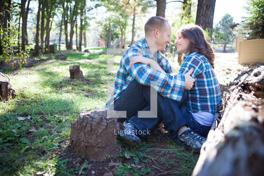 man and woman in plaid shirts snuggling in the woods 