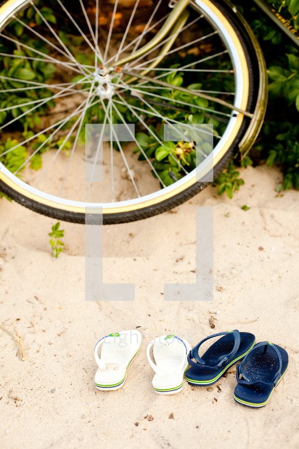 bicycle tire and flip flops in the sand 